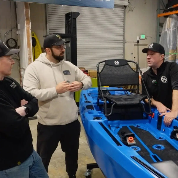 FluxJet team talking with visitors beside a blue FluxJet kayak in the factory