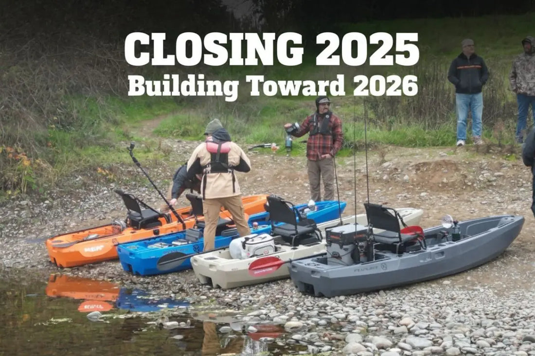 Lineup of FluxJet electric jet fishing kayaks in orange, blue, tan, and grey on the riverbank during end-of-year testing and 2026 production preparations.