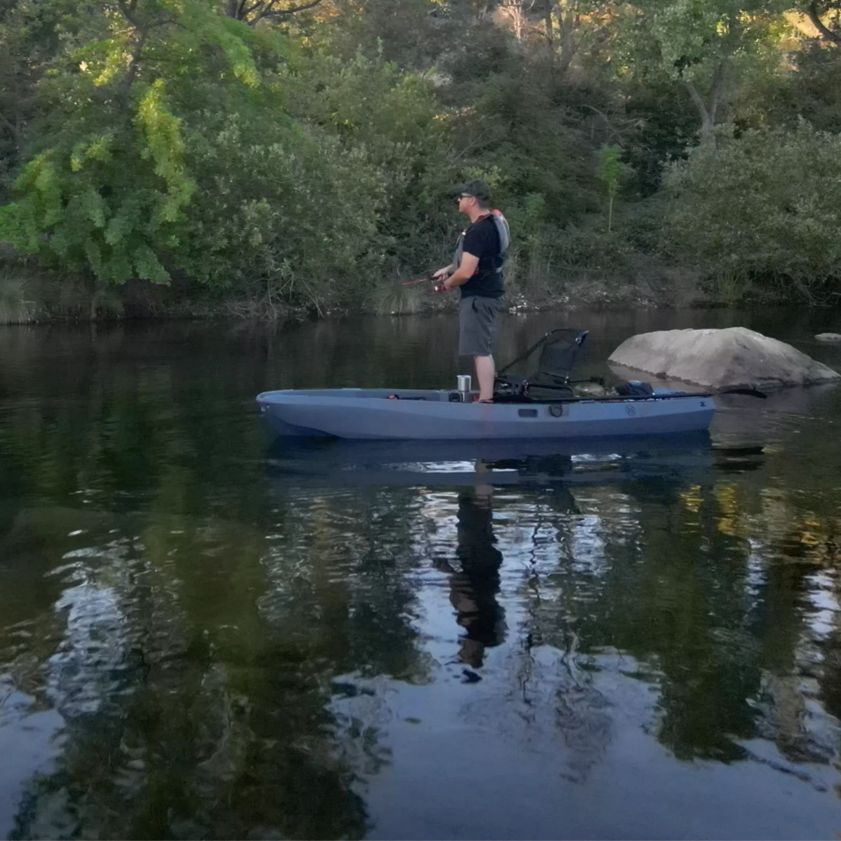 Angler standing and fishing from a gray FluxJet electric kayak