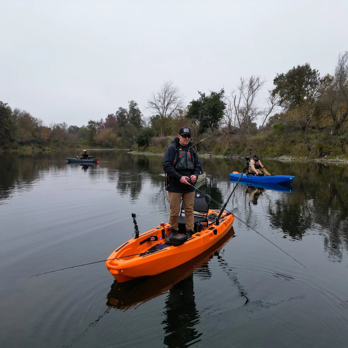 Angler standing and fishing from an orange FluxJet electric kayak on a river