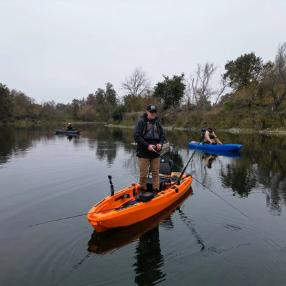 Angler standing and fishing from an orange FluxJet electric kayak on a river