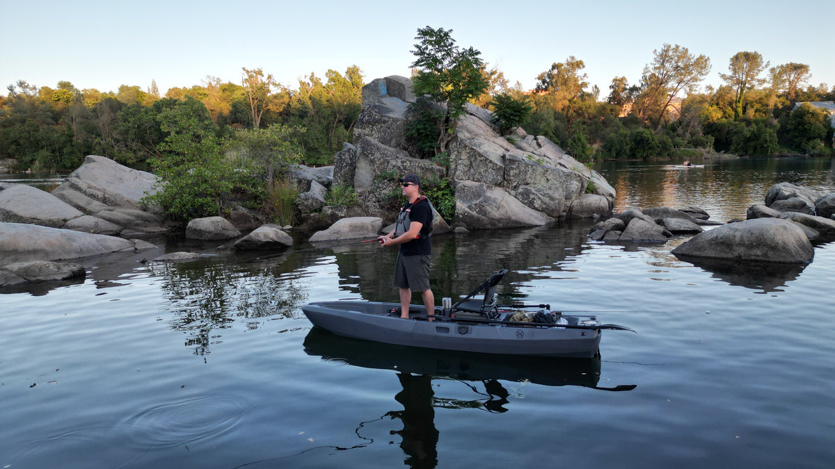 Man fishing from FluxJet electric kayak on calm rocky lake