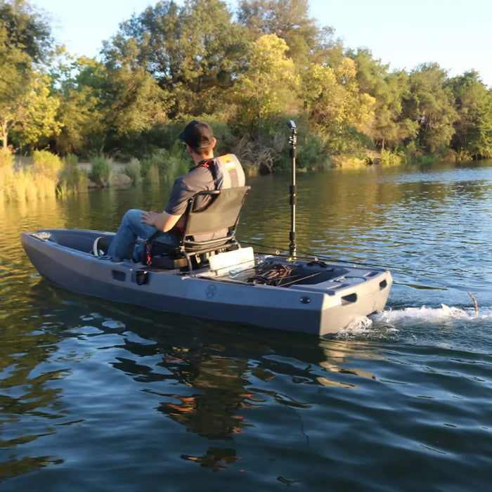 Angler fishing from a FluxJet electric jet kayak on a calm lake with trees behind