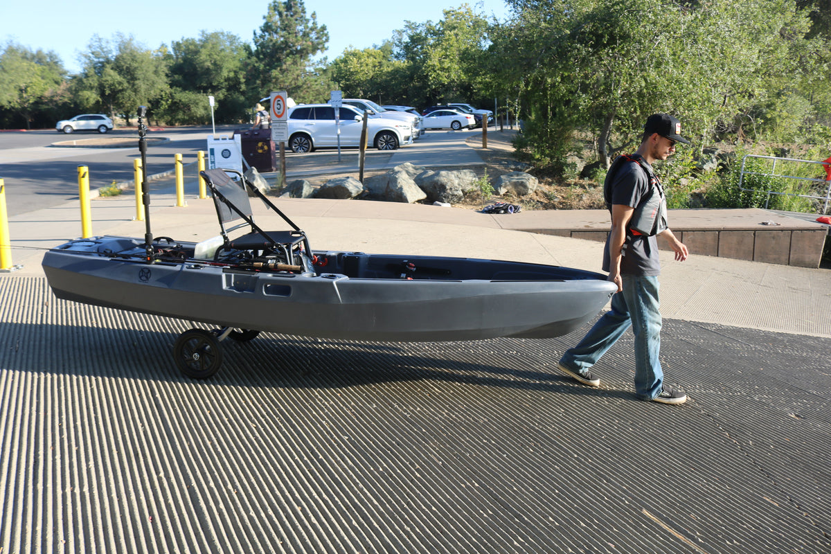 Man pulling FluxJet electric kayak on wheels at boat launch ramp