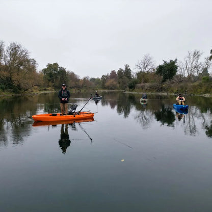  Anglers fishing from multiple FluxJet kayaks spread across a calm river, reflected on the water with trees lining the shoreline under an overcast sky.