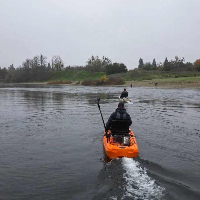 Two FluxJet kayaks traveling upriver in a line with small wakes on calm water