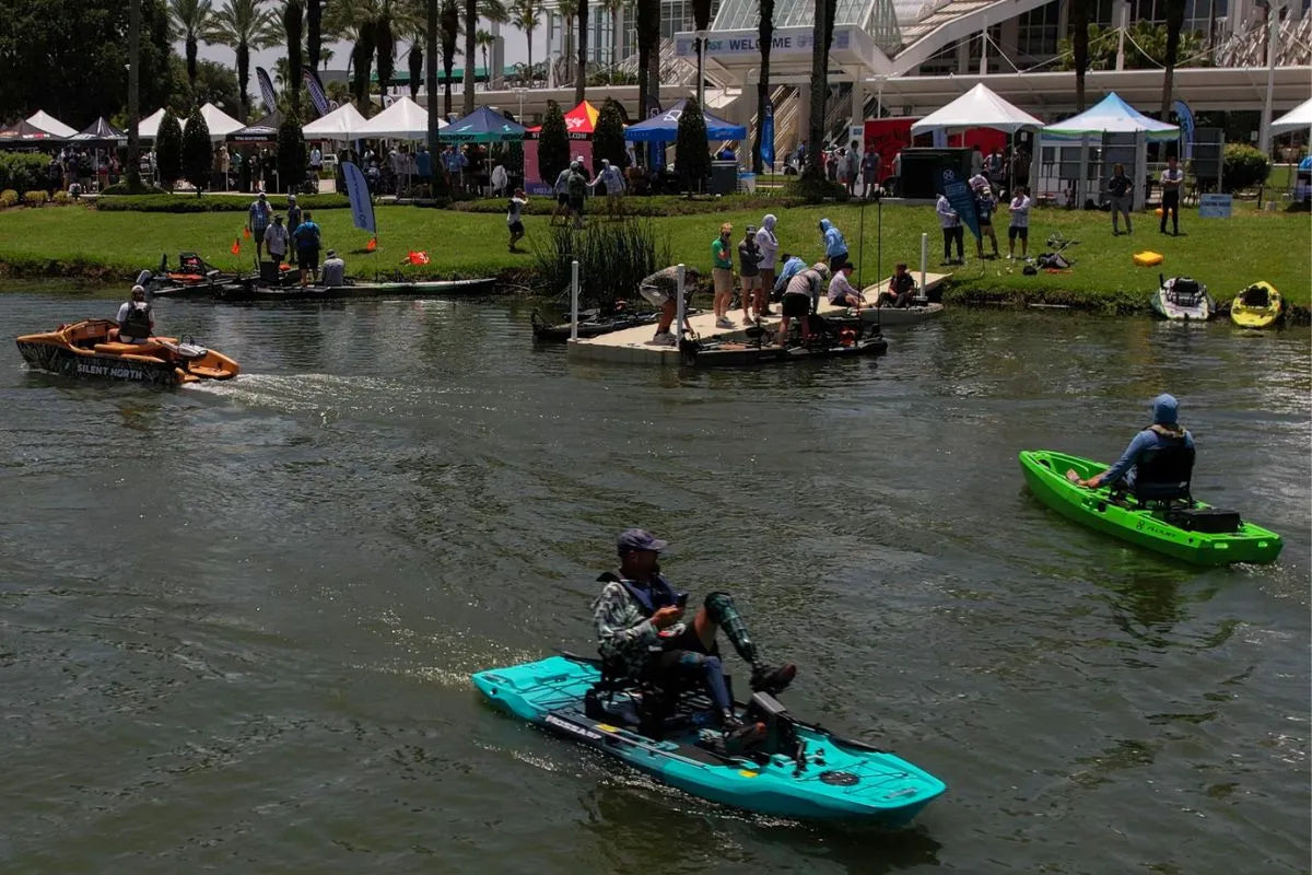 Angler pedaling a VoyaX Mossa 97 pedal-drive kayak, with a green FluxJet behind